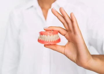 A hand holding a full set of upper and lower dentures