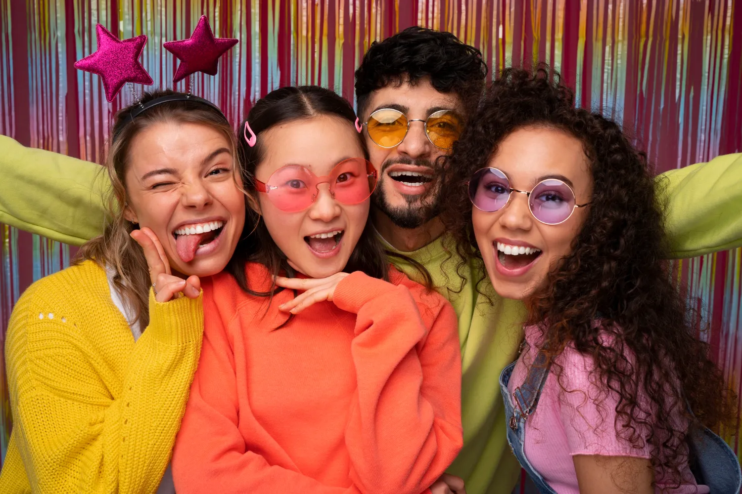 Group of smiling people wearing colourful party glasses and props