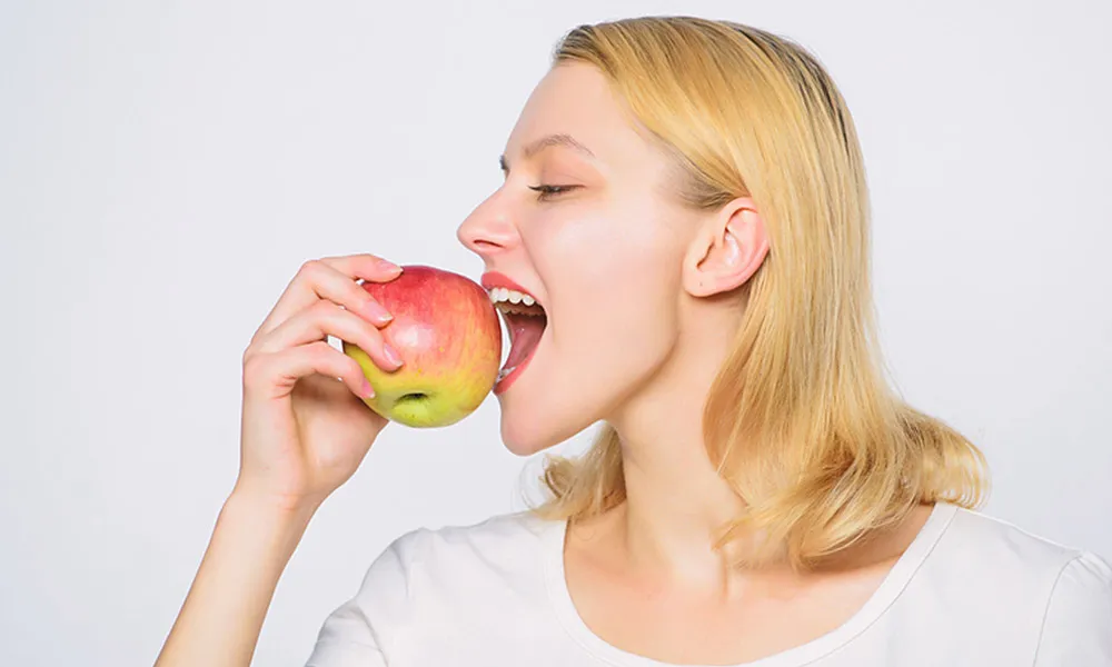 A woman biting into an apple