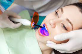 Patient reclining in the dental chair while a dentist works with a curing light